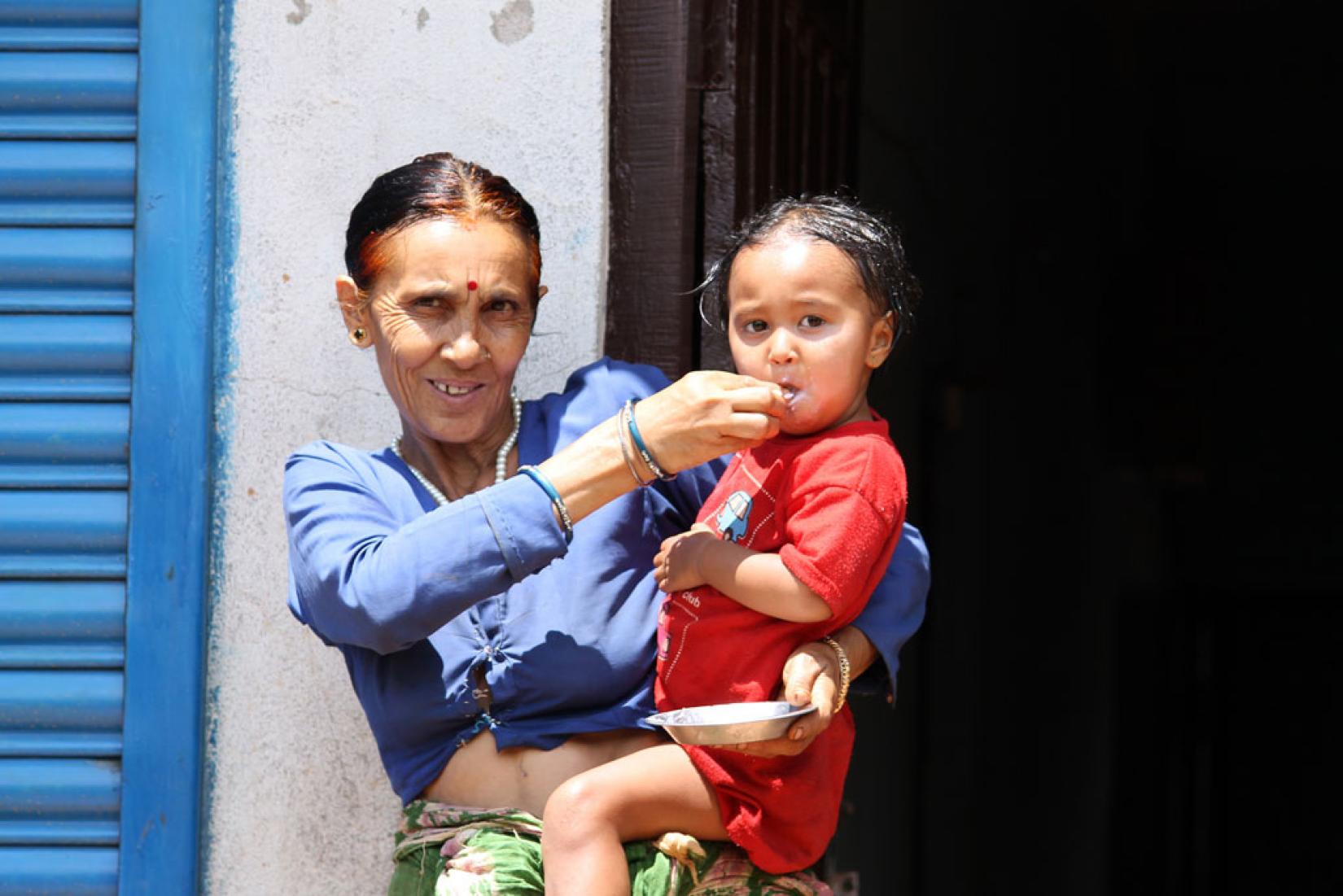 Avó alimenta neta de 2 anos no distrito de Dhading, no Nepal. Foto: Banco Mundial/Aisha Faquir