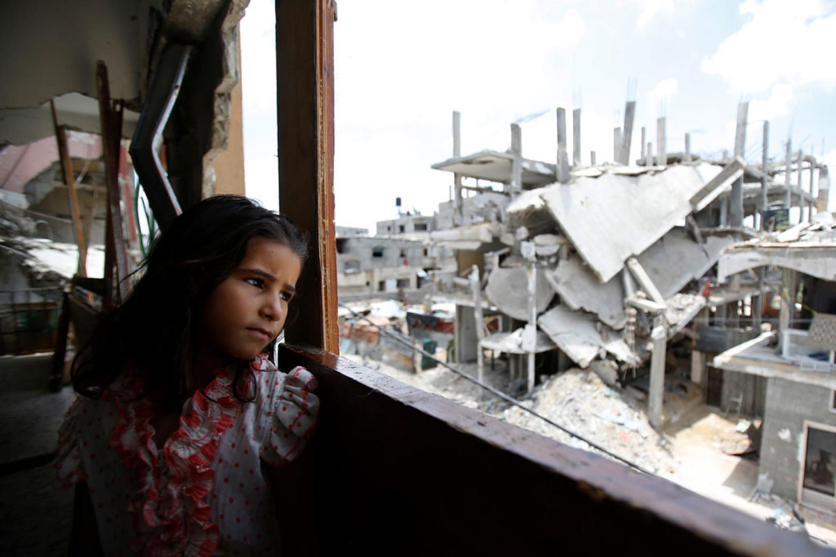 Menina palestina dentro da casa parcialmente destruída de sua família, olha a destruição no bairro de Shejaiya, em Gaza. Foto: UNICEF