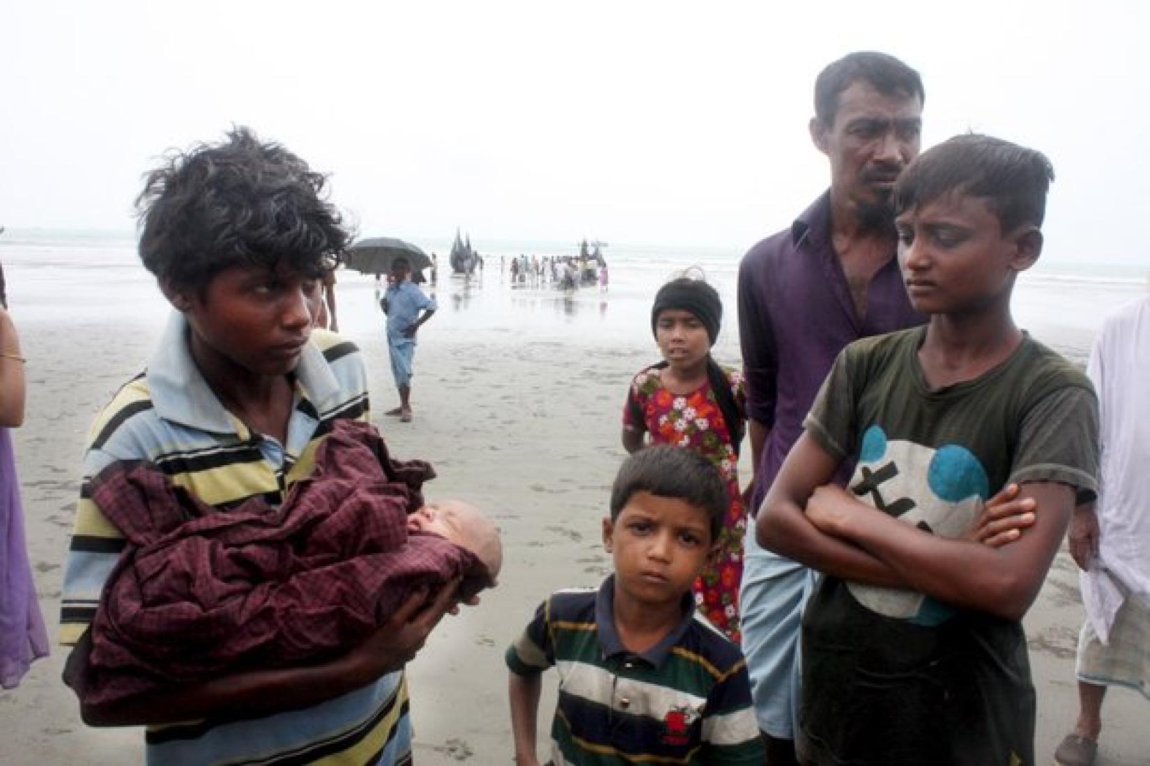 Um homem rohingya carrega seu filho recém-nascido enquanto sua família estava se escondendo na selva, após terem sido forçados a fugir da violência em Rakhine, no norte de Mianmar. A família desafiou o mar agitado da Baía de Bengala para chegar a Teknaf, região no sudeste de Bangladesh. Foto: ACNUR/Vivian Tan