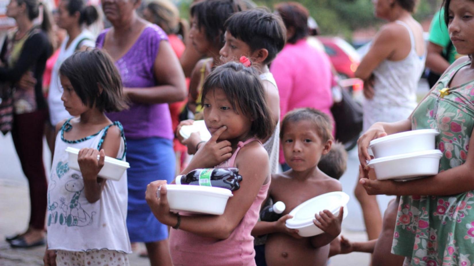 Venezuelanos que vivem na Praça Simón Bolívar, em Boa Vista, fazem fila para receber alimentos fornecidos por membros da comunidade local. Foto: ACNUR/Reynesson Damasceno