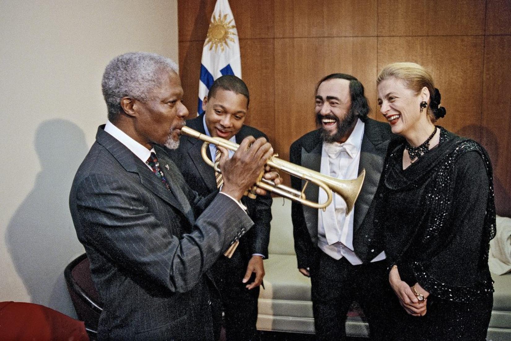 Então  secretário-geral da ONU, Kofi Annan, toca trompete após aula rápida com o músico Wynton Marsalis, junto ao cantor Luciano Pavarotti e Nane Annan, em 10 de dezembro de 1998. Foto: ONU/Evan Schneider