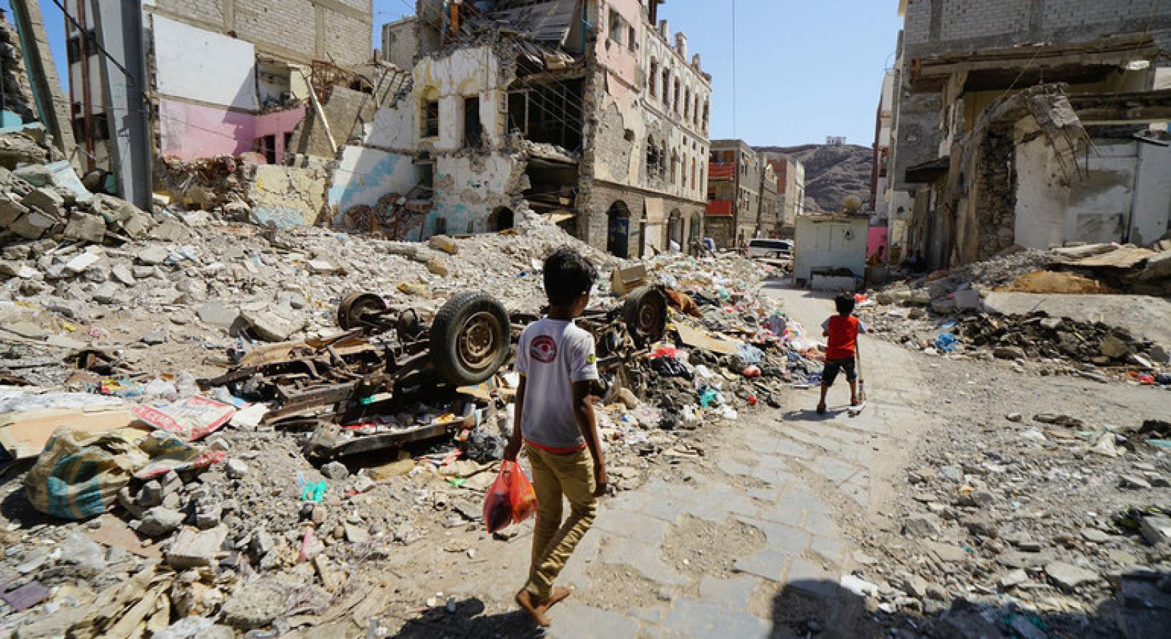 Crianças caminham por uma parte do centro de Craiter, em Aden, no Iêmen. A área foi seriamente danificada pelos ataques aéreos em 2015, quando os houthi foram expulsos da cidade pelas forças da coalizão. Foto: OCHA / Giles Clarke