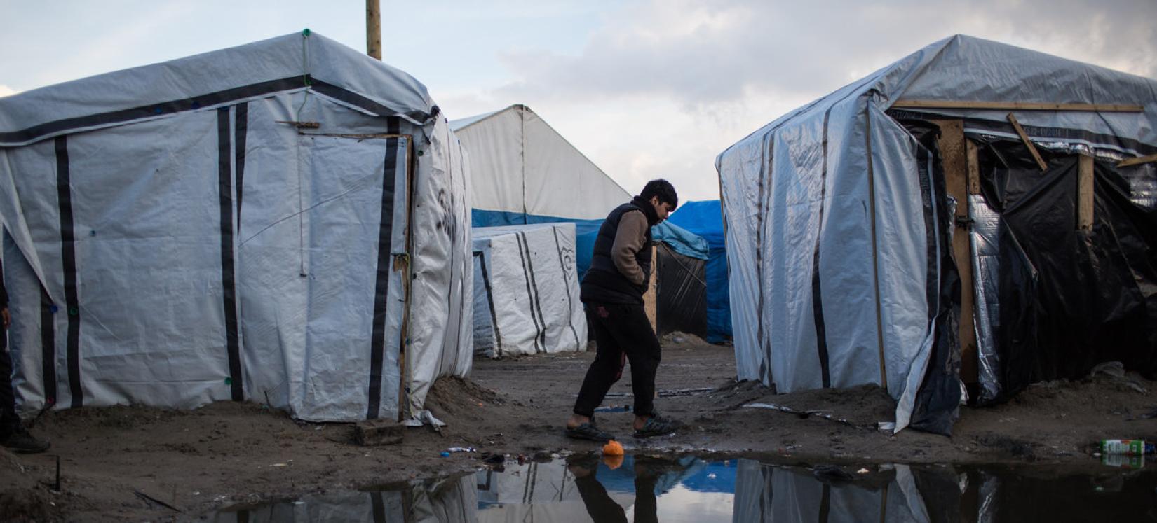 Menino caminha por um acampamento de migrantes em Calais, França. De acordo com as estimativas, cerca de 900 migrantes e requerentes de asilo estão abrigados na área, muitos sem banheiros ou lavatórios.