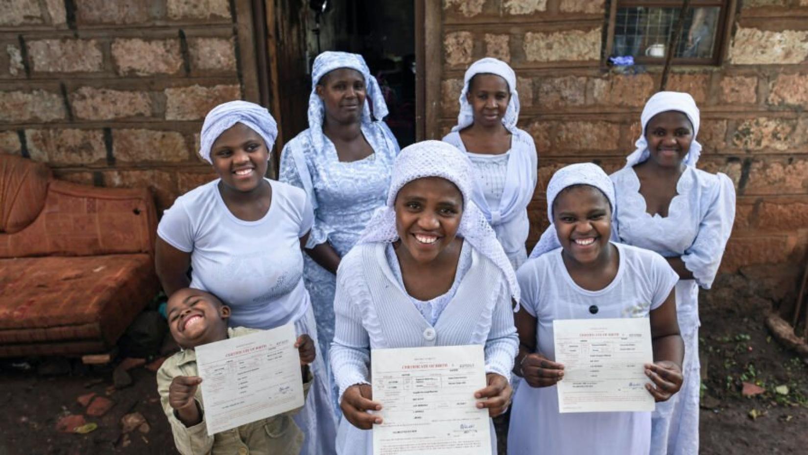 Mulher Shona apátrida, Nosizi Reuben (no centro) posa com sua família enquanto segura sua certidão de nascimento recém-emitida em Kinoo, Quênia.