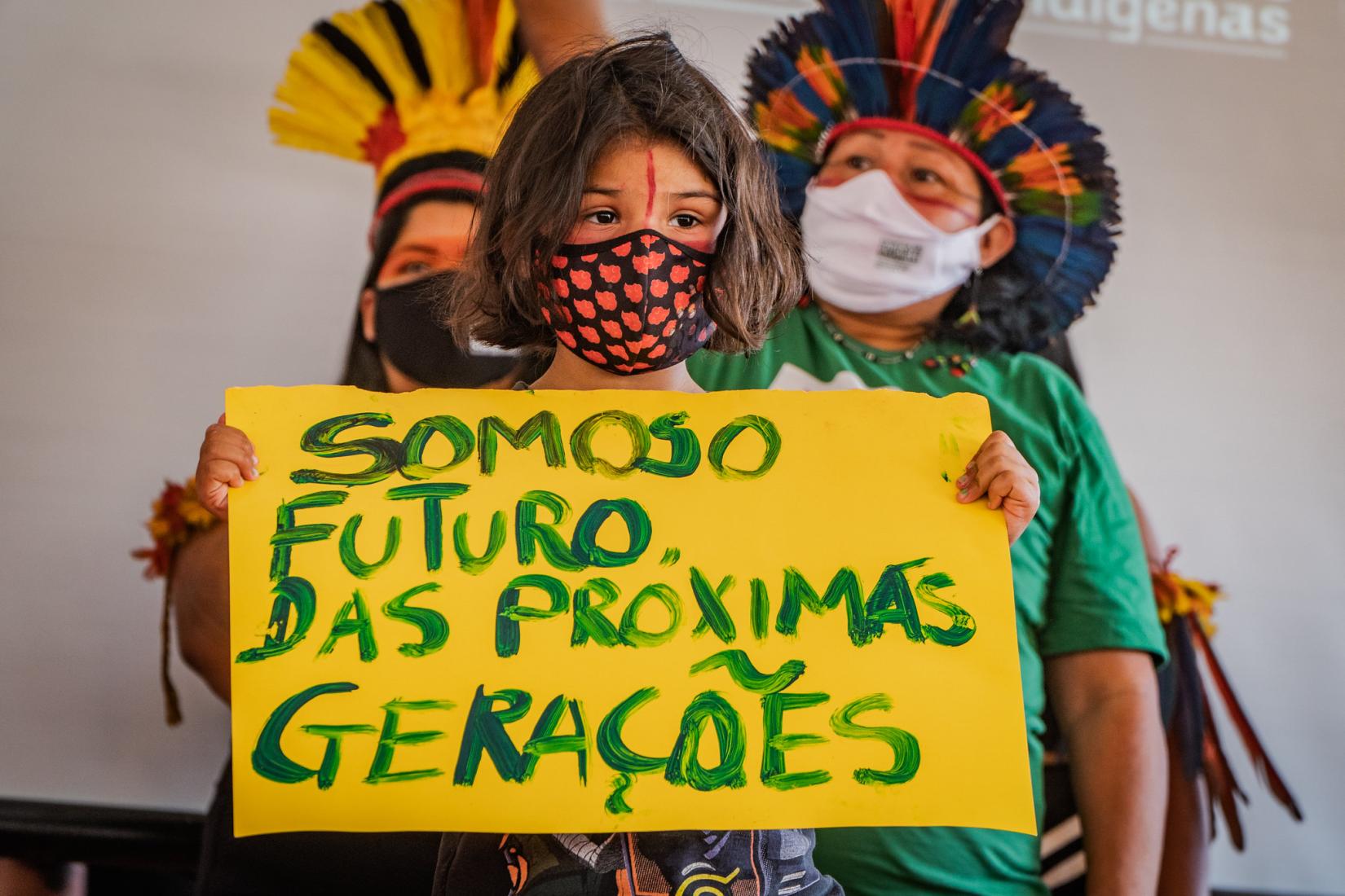 menina indígena segura cartaz em que se lê somos o futuro das próximas gerações
