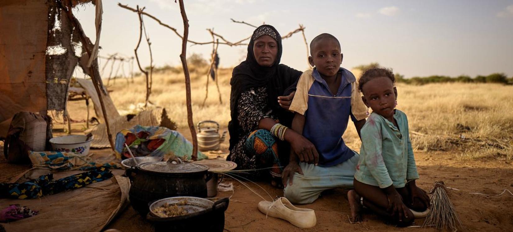 Uma família deslocada senta-se em frente à sua tenda num acampamento informal em Bagoundié, no Mali.