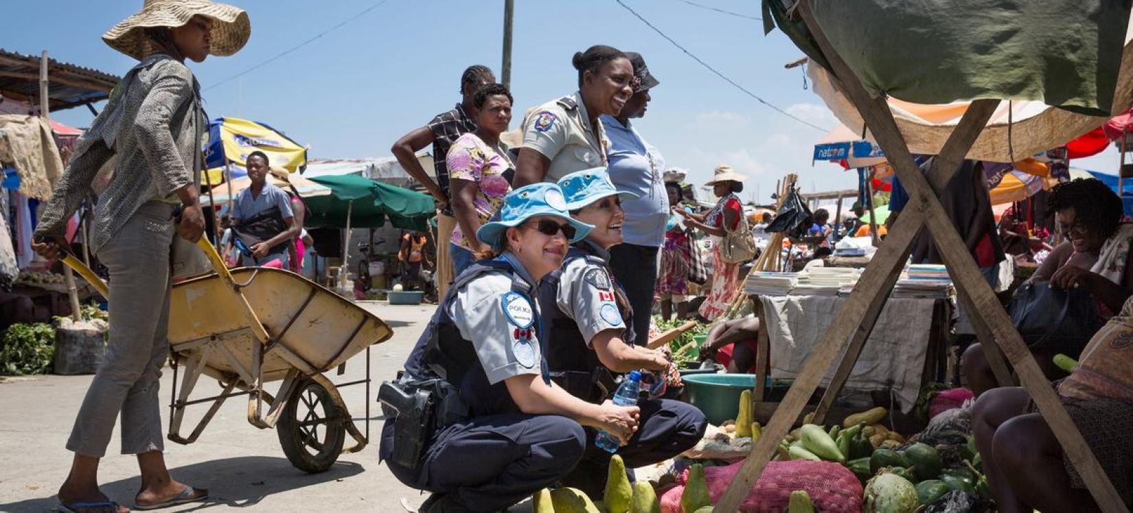 Duas policiais canadenses servindo no Haiti conversam com mulheres locais sobre os esforços da ONU para combater a exploração e o abuso sexual.