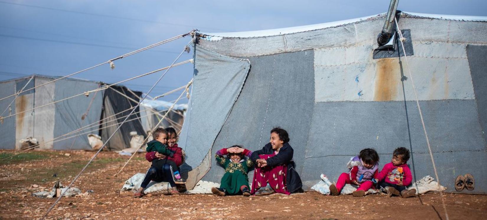 Crianças sentadas do lado de fora da barraca da família no acampamento improvisado de Alzhouriyeh, na zona rural de Homs, na Síria.