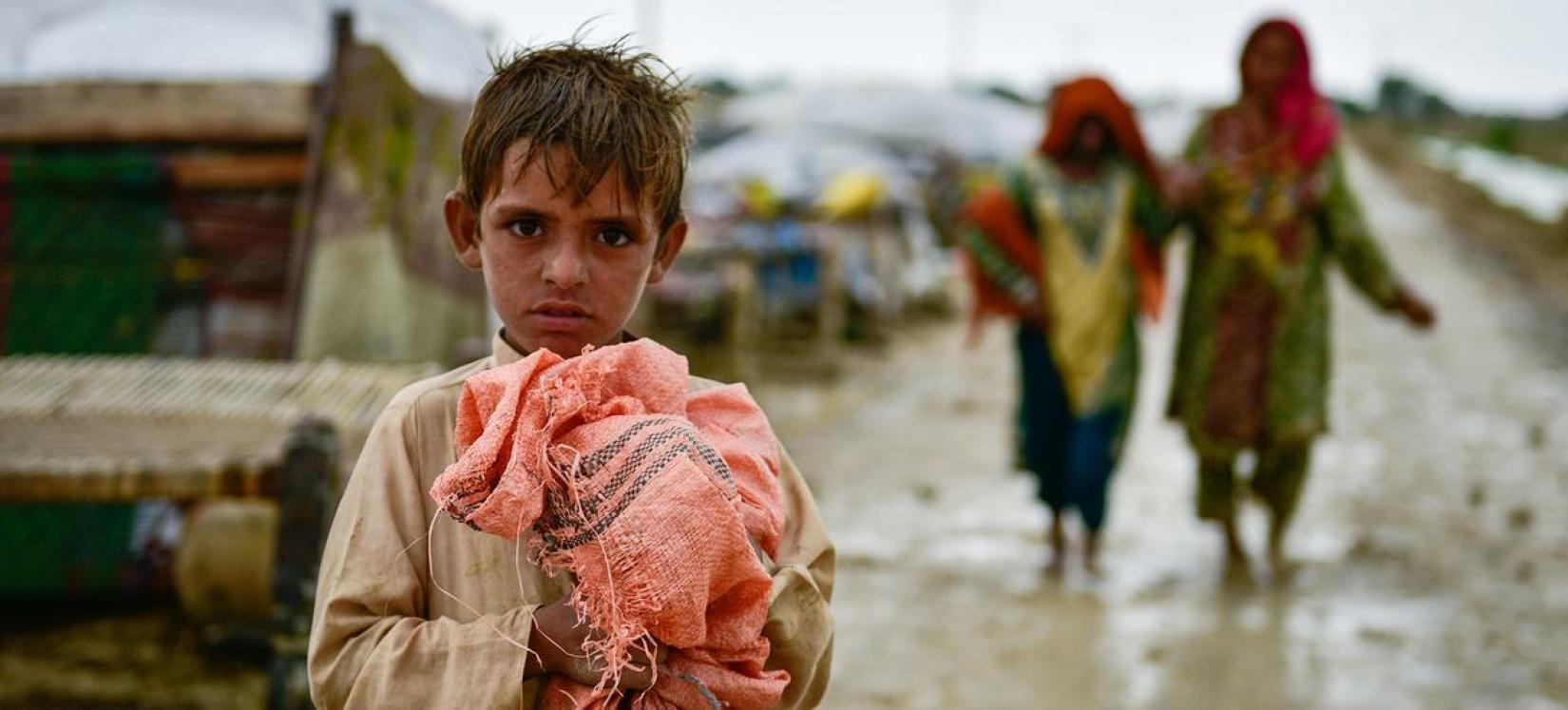 Uma criança segura seus pertences após inundações na província de Balochistan, no Paquistão.