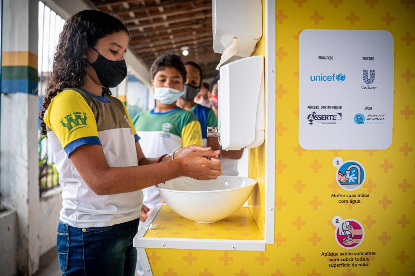 A estudante Maria Lara Vitória da Silva, de 10 anos, lava as mãos e comemora o fato da nova pia proteger as crianças de vários tipos de vírus. 