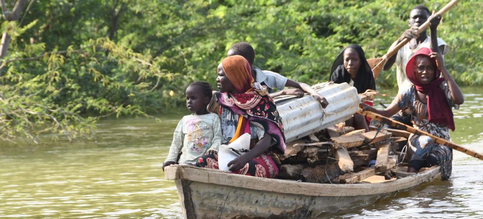 Uma família que perdeu sua casa para as inundações transporta o que resta de sua casa por canoa escavada no Camarões.
