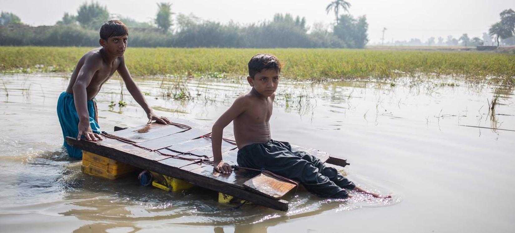 Crianças voltam para casa em água contaminada da enchente no Paquistão.