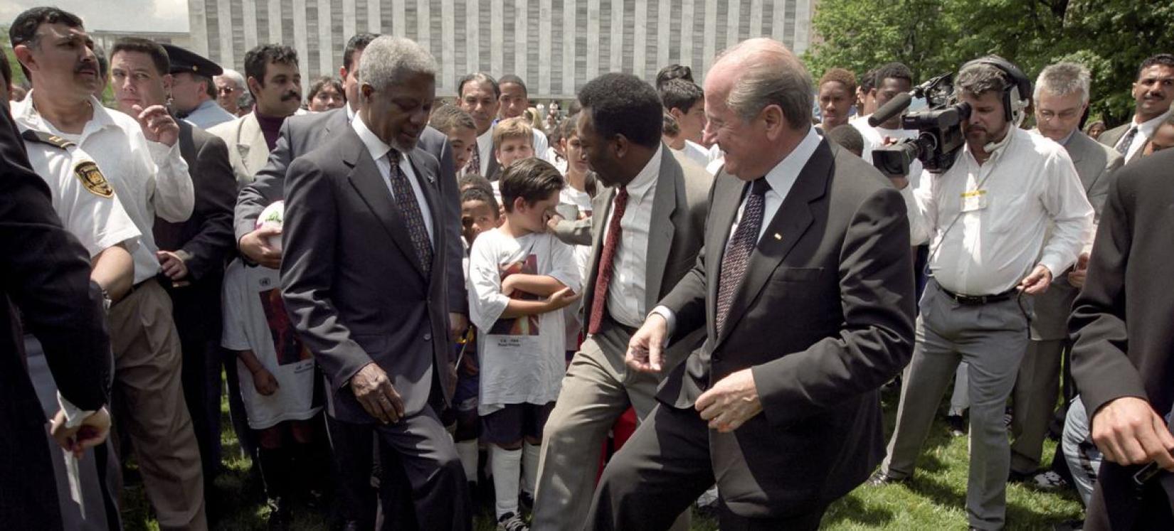 [Da esquerda para a direita] ao redor de uma bola de futebol estão o ex-secretário-geral da ONU Kofi Annan, o astro do futebol brasileiro Pelé e o presidente da FIFA, Joseph Blatter, em uma coletiva de imprensa anunciando sua decisão de ingressar em um relacionamento cooperativo com a FIFA para promover as Nações Unidas.