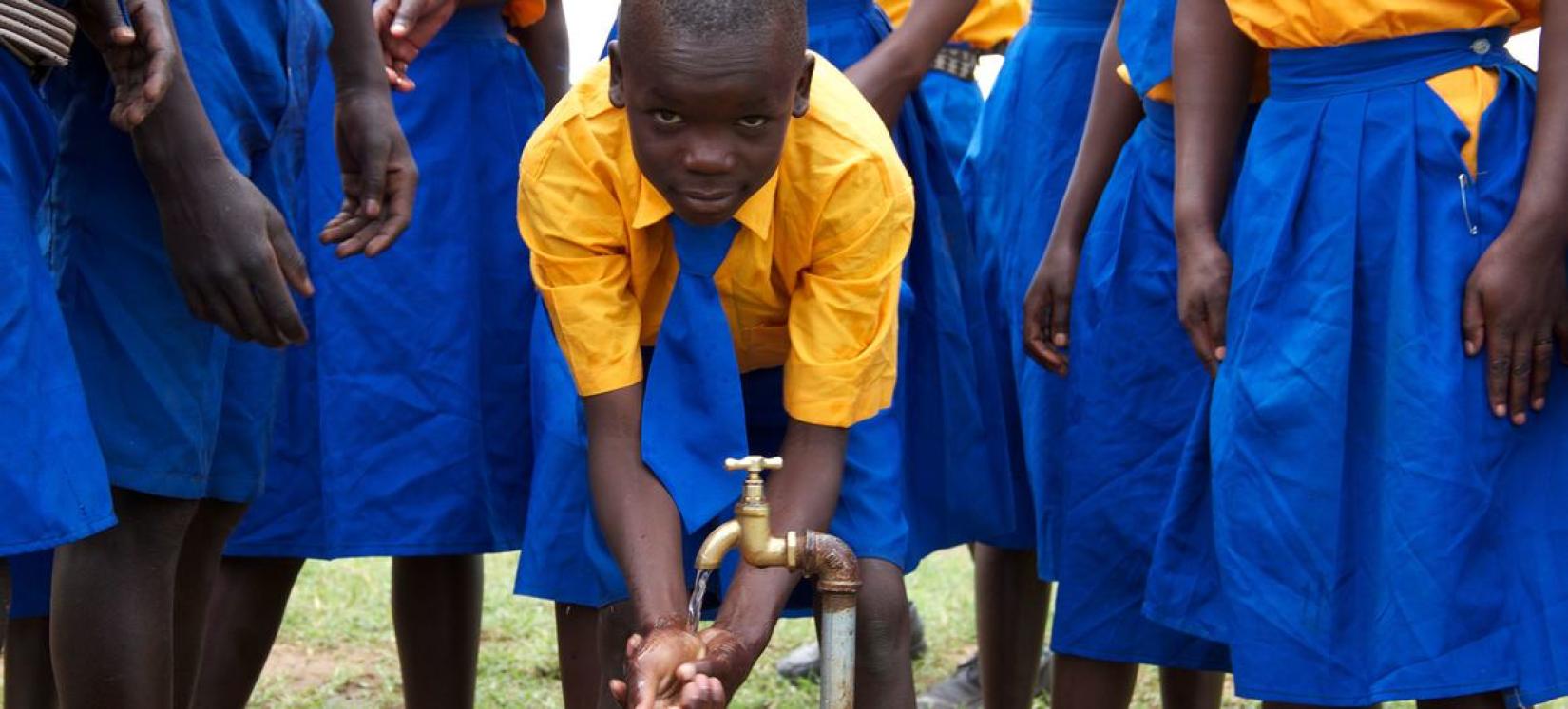 Crianças lavam as mãos em um sistema de água instalado em sua escola no nordeste de Uganda.
