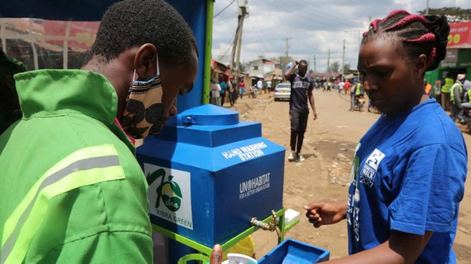 Uma mulher usa uma das instalações de lavagem de mãos instaladas pelo Programa das Nações Unidas para os Assentamentos Humanos (UN-Habitat) na favela de Kibera, em Nairóbi. 