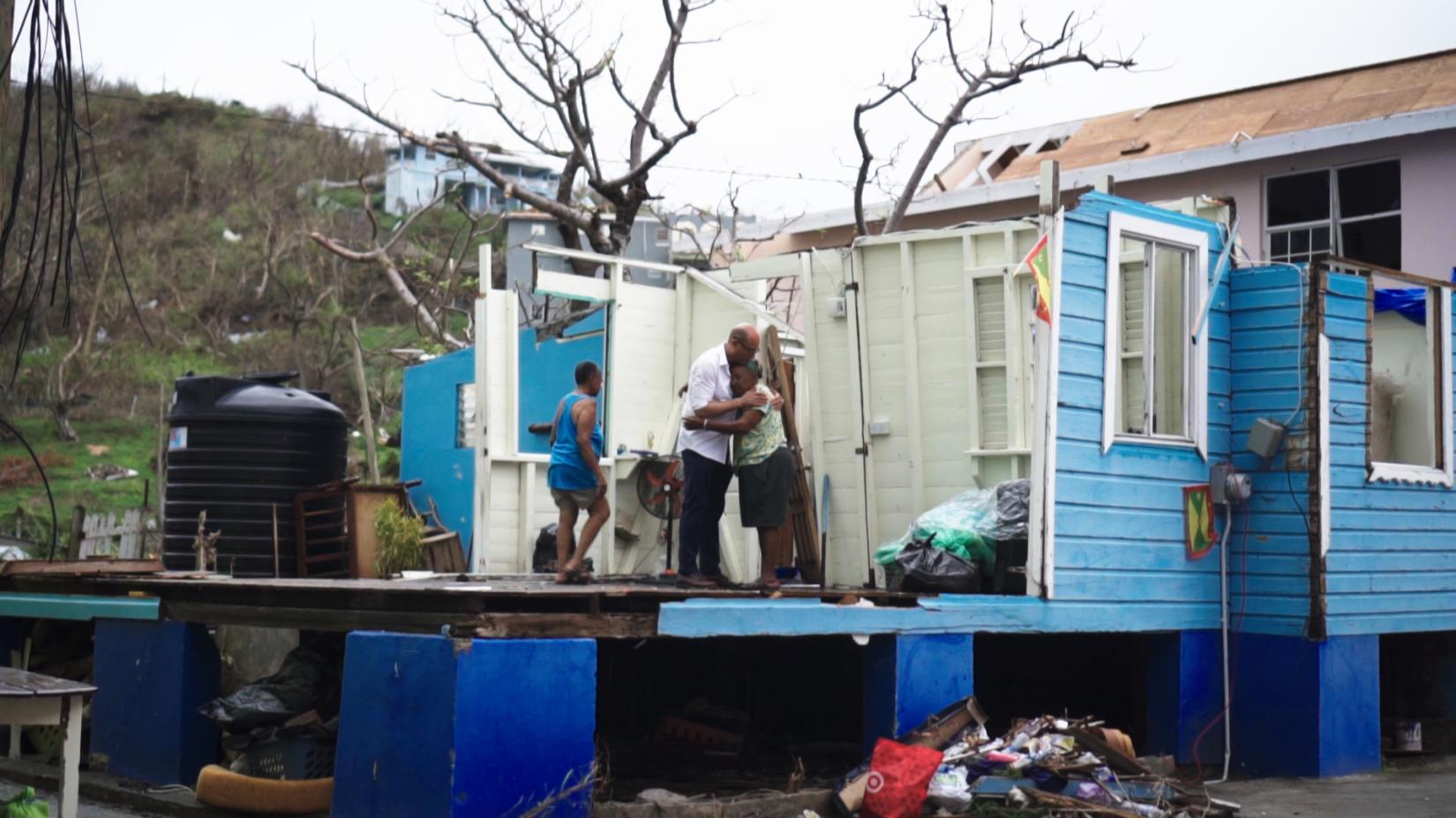 O secretário executivo da ONU Mudanças Climáticas, Simon Stiell, conforta uma vizinha perto da casa da sua avó em Carriacou.