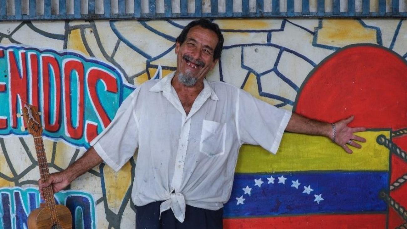O artista Ramos mostra com alegria um dos murais que pintou no abrigo Tancredo Neves, em Boa Vista (RR).