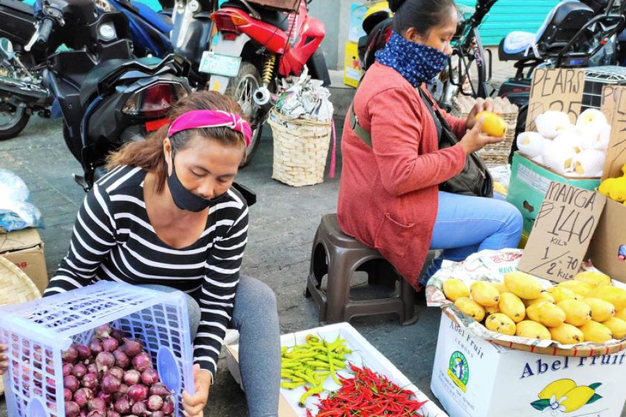 Mulheres vendem frutas e vegetais numa calçada nas Filipinas, onde os trabalhadores na economia informal estão em perigo por ter o sustento destruído pelos impactos da COVID-19