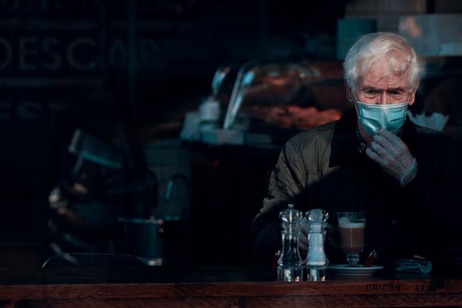 Homem usa máscara e luvas enquanto toma um café em Glashow, na Escócia