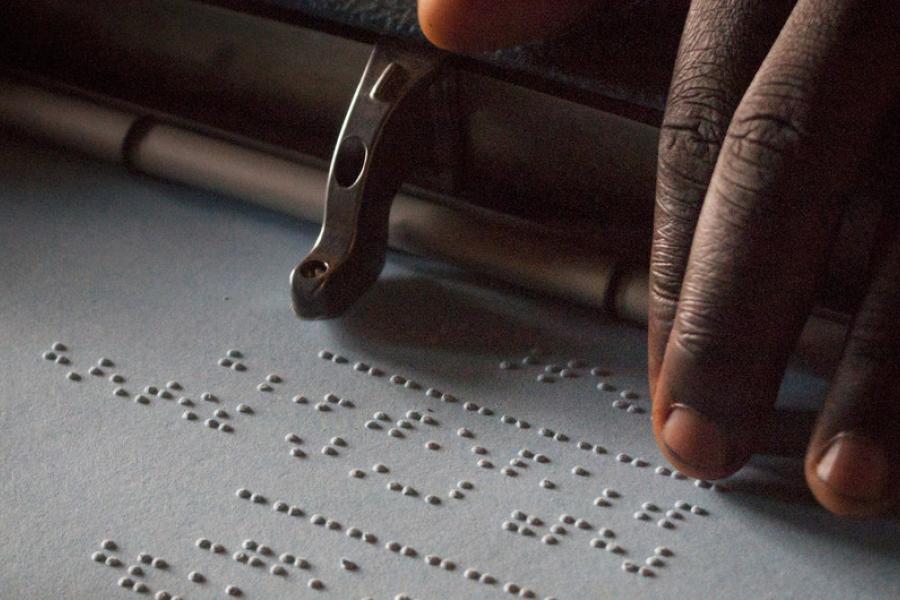 Criança com deficiência visual lê em Braille numa escola em Uganda. 
