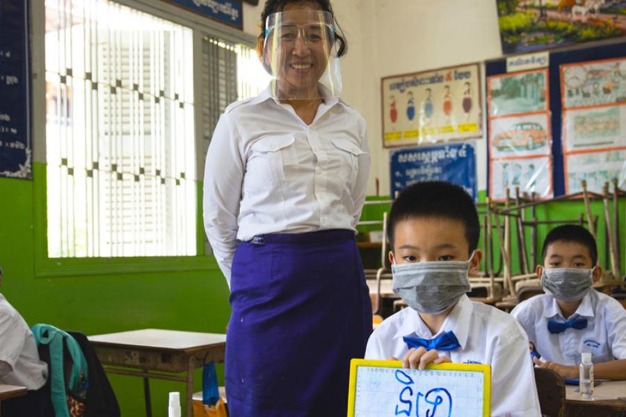 Professora e alunos usam máscaras e fazem distanciamento físico em escola primária em Phnom Penh, no Camboja. 
