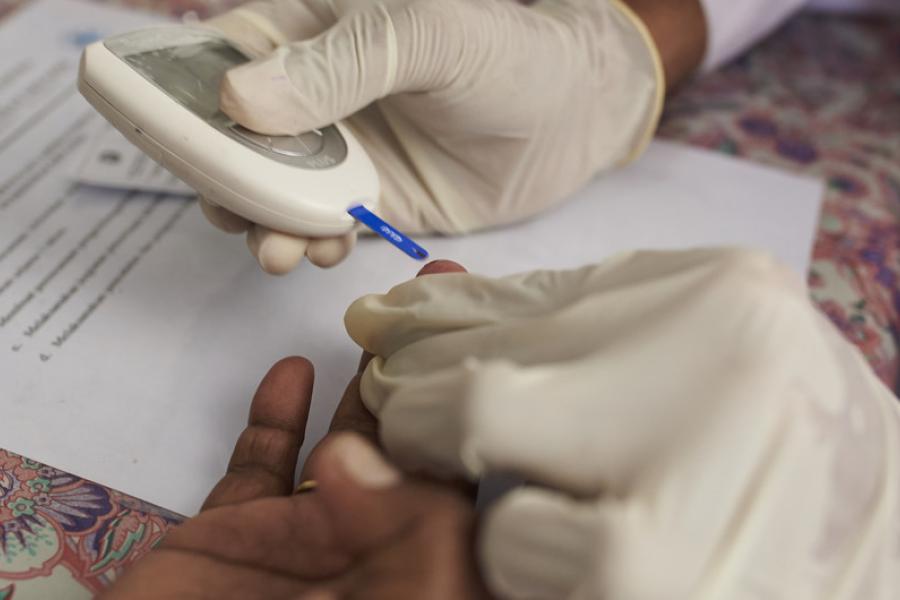 Um profissional de saúde verifica o nível de açúcar no sangue de uma mulher em um centro de saúde comunitário na Indonésia
