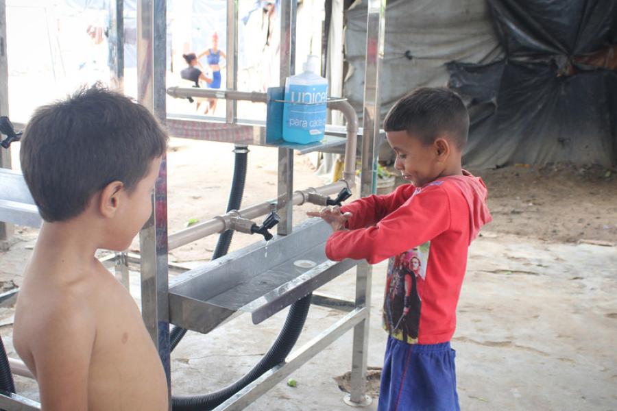 crianças lavam as mãos em estrutura montada por UNICEF