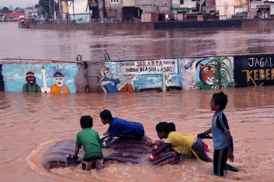 Crianças brincam nas águas de enchentes do Rio Ciliwung, leste de Jakarta, Indonésia