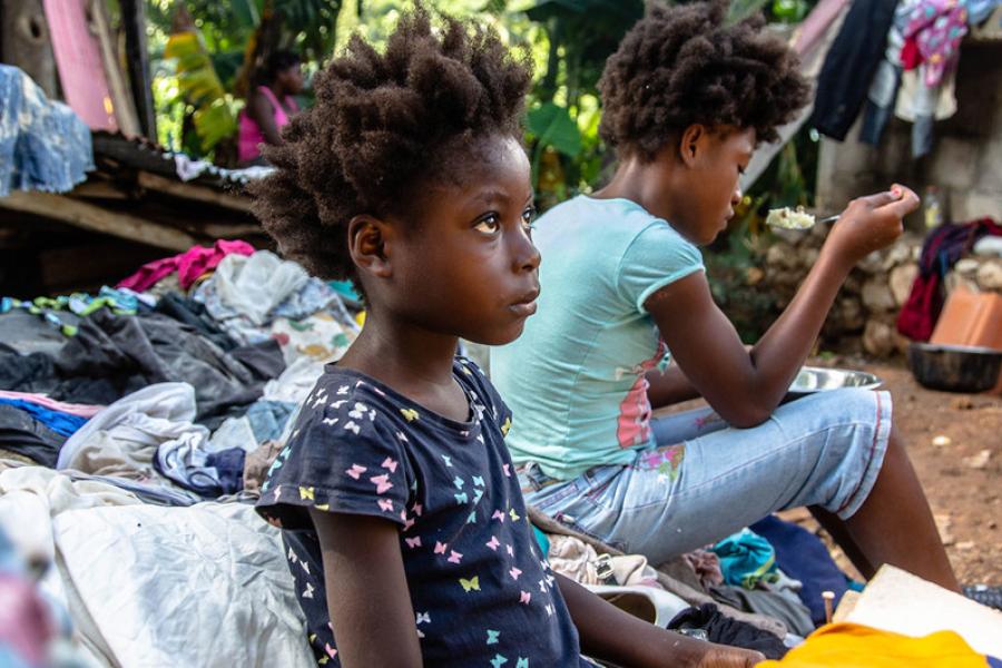 Uma família se alimenta, sentada nos escombros da casa que eles perderam em um terremoto de magnitude 7,2 no Haiti