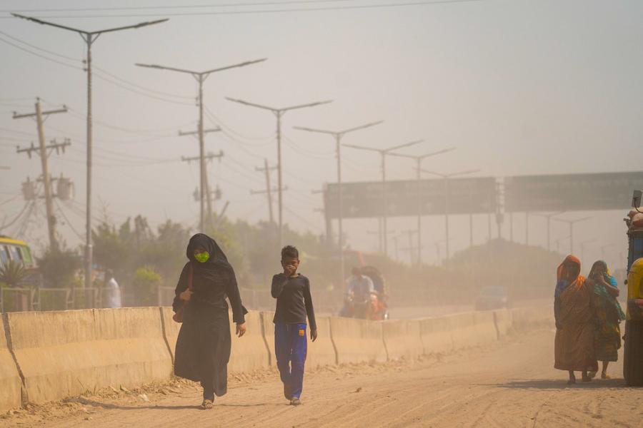 pessoas caminham em meio à poluição