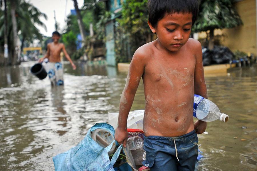 Um menino arrasta seus pertences pelas ruas inundadas de Manila após um tufão nas Filipinas (arquivo)