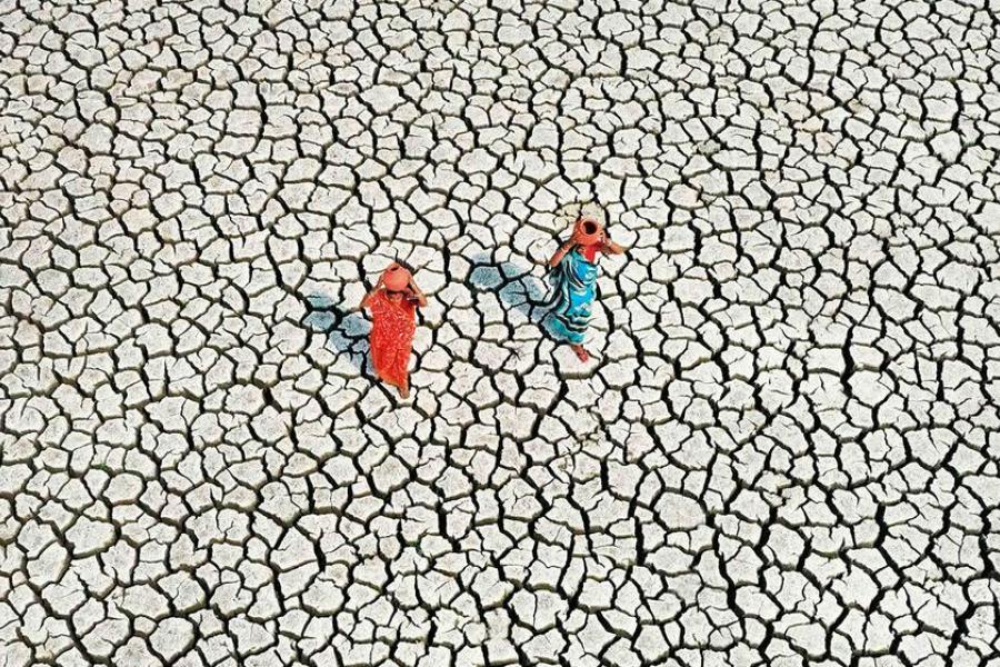 Em terreno gravemente afetado pela seca, duas mulheres procuram o abastecimento diário de água na Índia