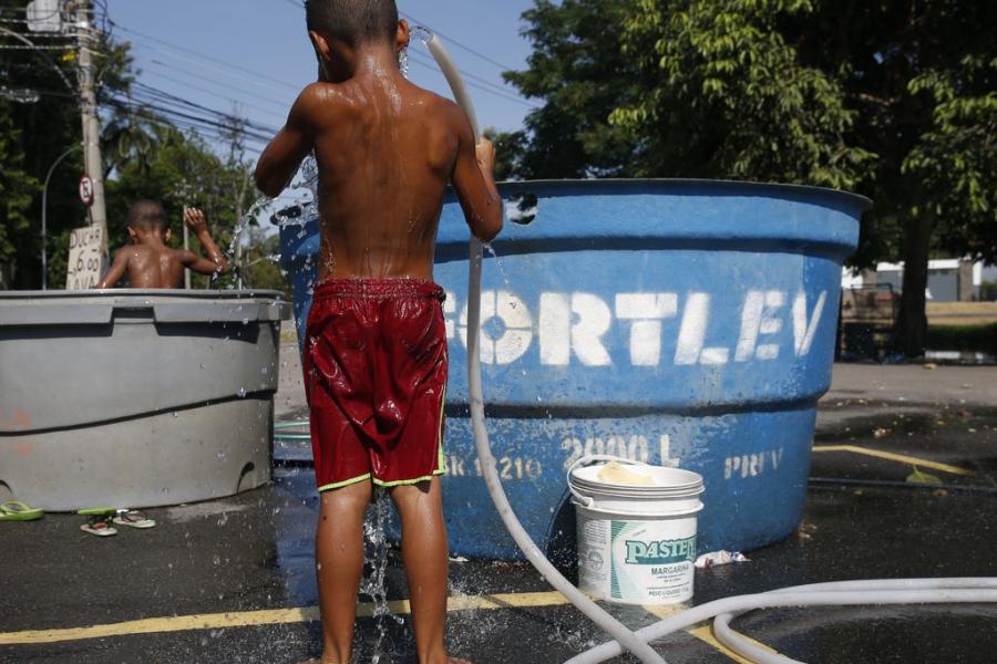 menino se refresca com banho de mangueira