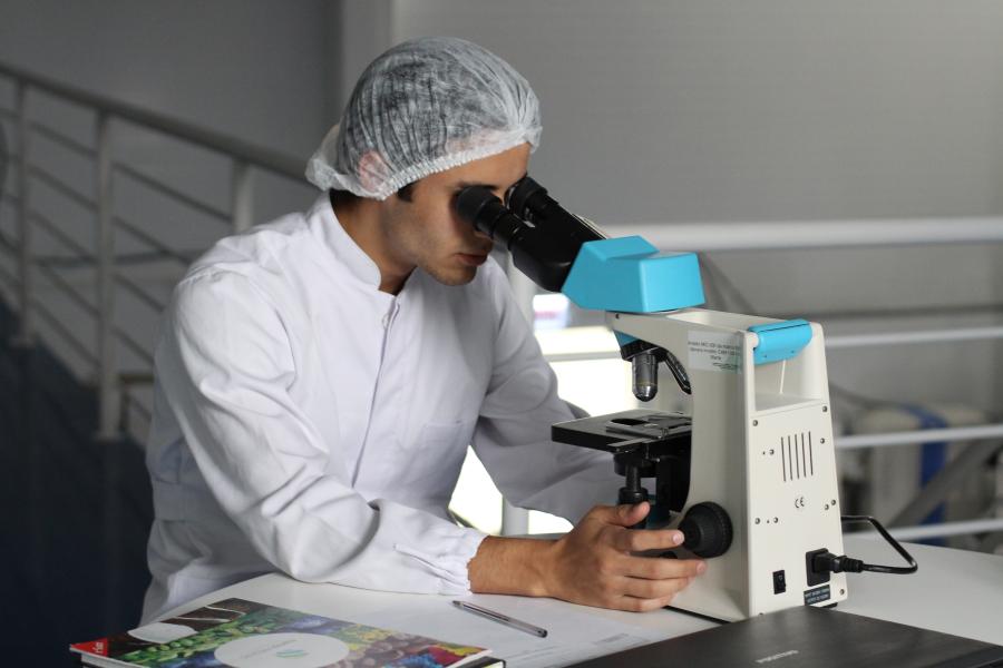 cientista olha por um microscópio