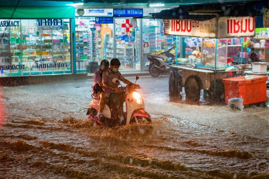 Duas pessoas andam pela chuva de monção e inundações pesadas em uma moto