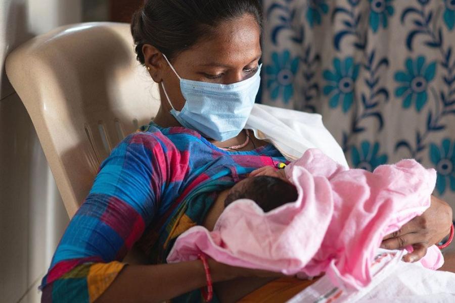 Mulher amamenta seu bebê em uma sala de parto na Índia logo após o parto
