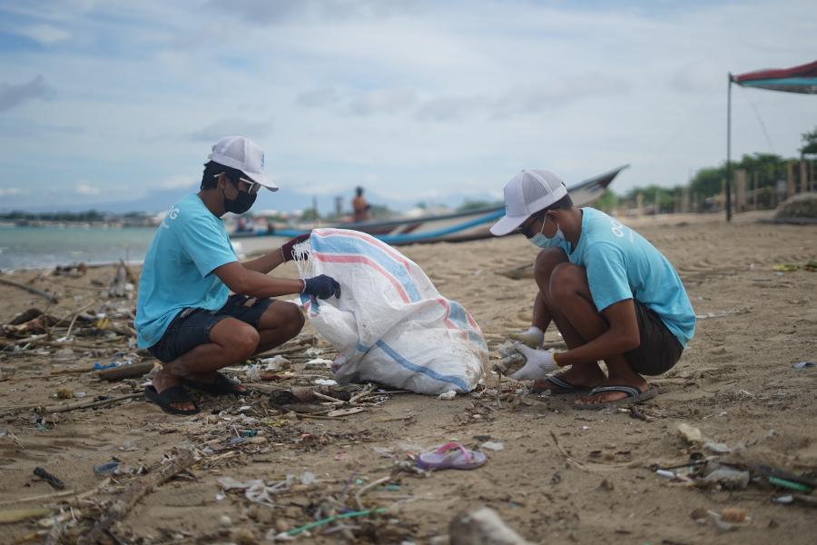 Dois homens indonésios limpam a praia em nome do grupo de limpeza do oceano